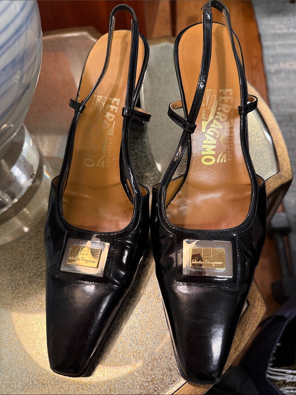 Salvatore Ferragamo Black Patent Slingback Pumps with Gold Logo Plaque.
